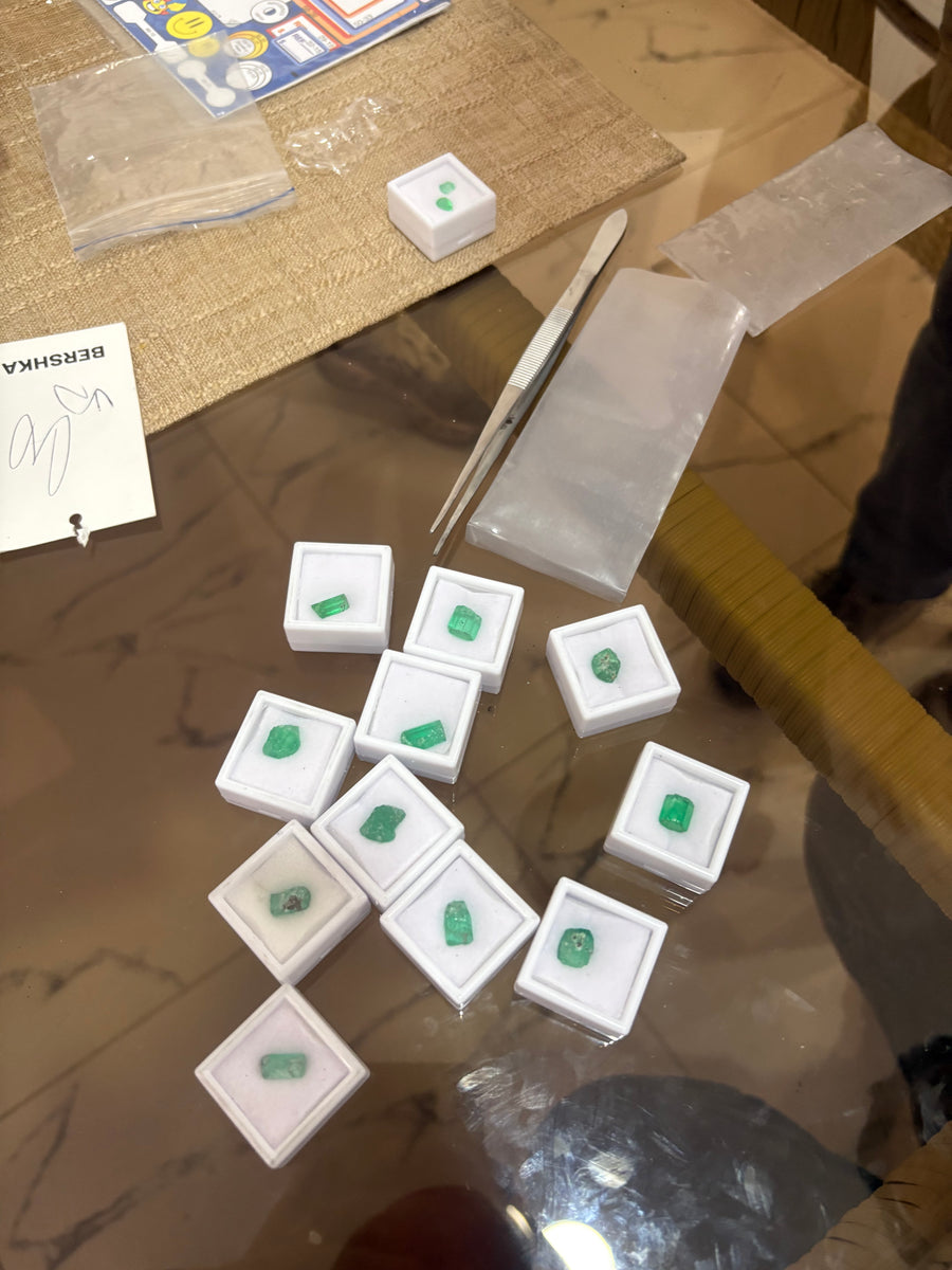 Cut emeralds in their boxes, laid out on a trading table